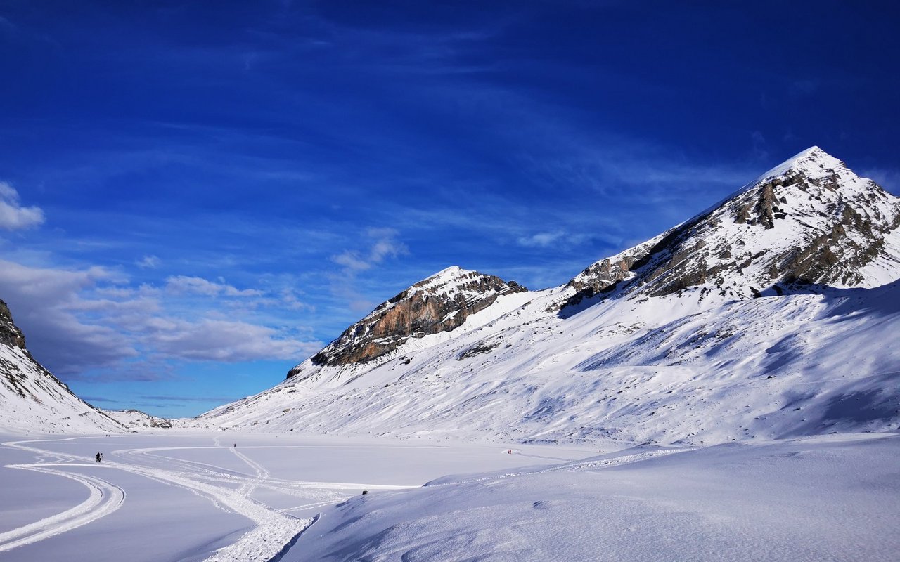 Der idyllisch auf 2200 Metern gelegene Daubensee im Wallis wird im Winter mit seiner beeindruckenden Alpenkulisse zu einem beliebten Ziel für Schlittschuhläufer und Winterwanderer.